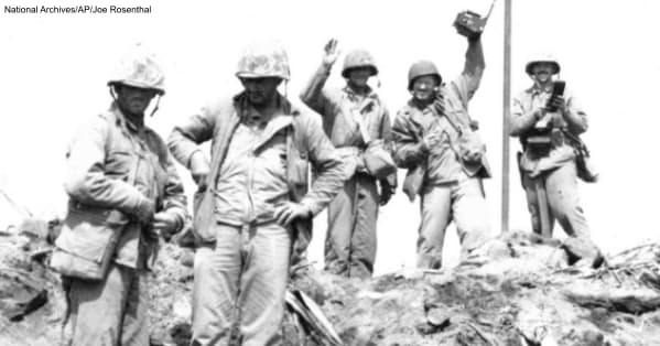 John Bradley is standing to the left in this photograph. His cuffed pants and clothing is not consistent with the flag raising photo.