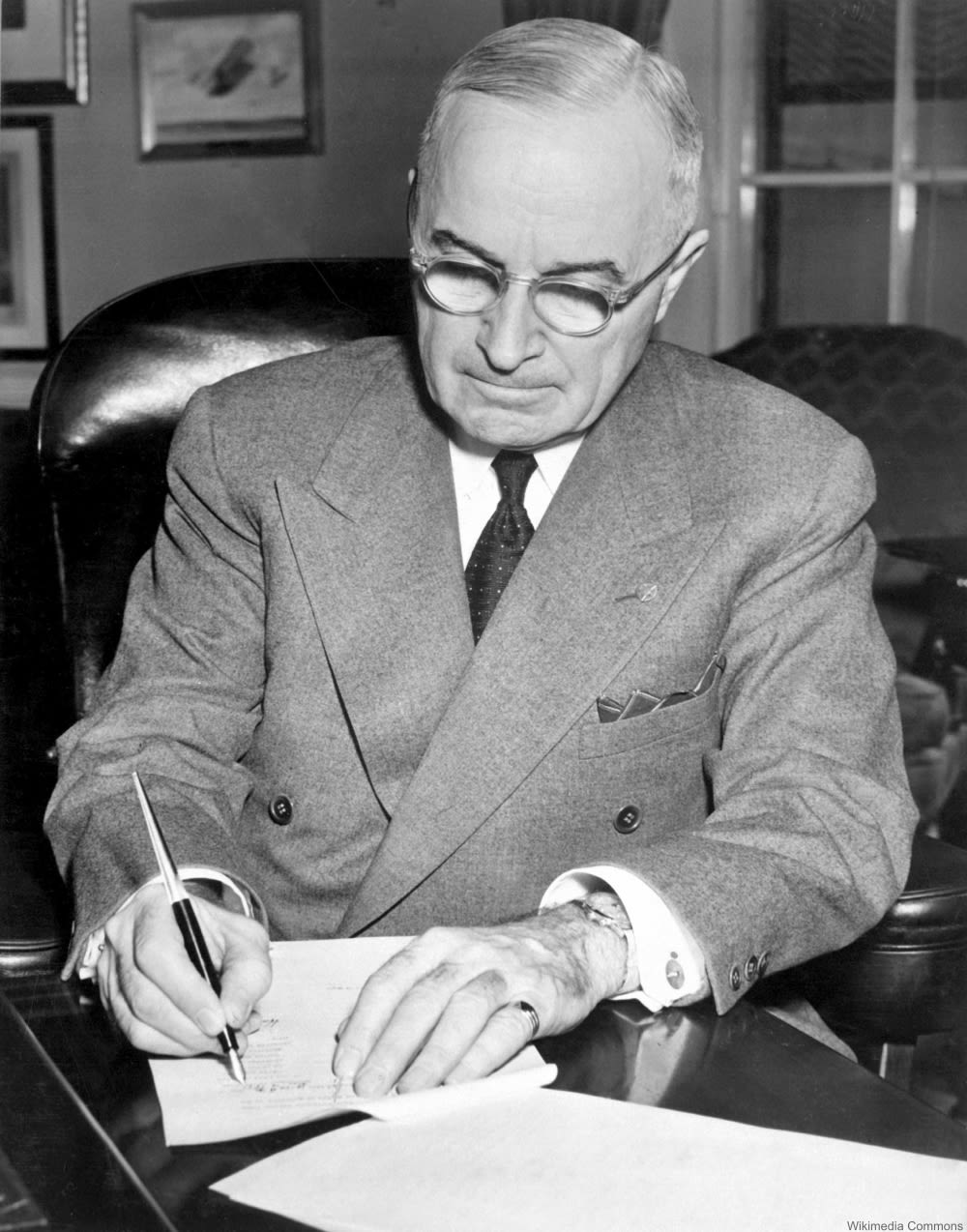 President Harry S. Truman is shown at his desk at the White House signing a proclamation declaring a national emergency. December 16, 1950.