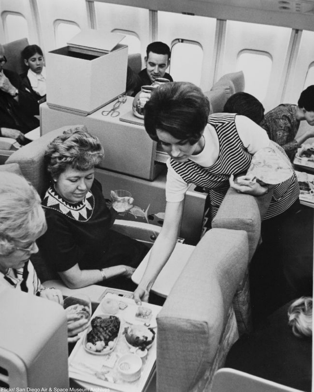 Pacific Southwest Airlines stewardess serving a meal.