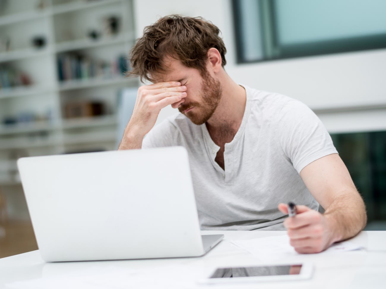 Tired man working online at home on a laptop computer - freelance designer