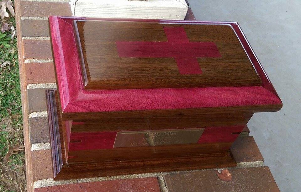 From Justin Fulton: I had the honor of making this crematory urn of walnut and purple heart. The lid has a double onlay and is inlaid with a cross. The body also has a wrapped Inlay and keyed miter joints of contrasting woods. This was my first inlay and first keyed miters.