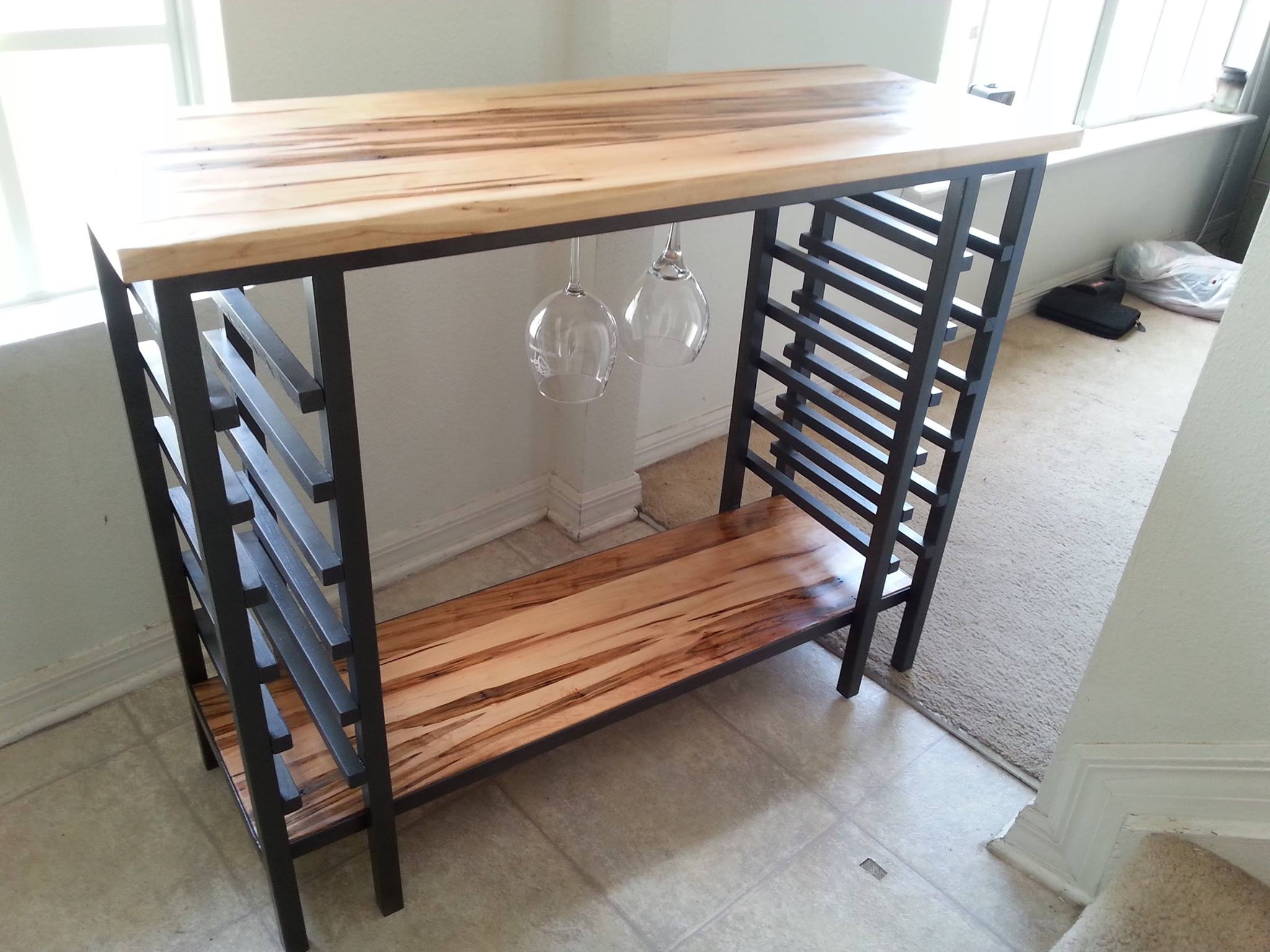 From Nick Lyman: It is a custom wine rack made as a wedding gift for my sister. The frame is welded steel and the surfaces are Ambrosia Maple finished with true tung oil. It holds 12 wine glasses in hangers and 12 wine bottles in the vertical racks.