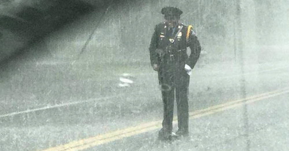 Source: InspireMore An officer stands in the rain, grinning.