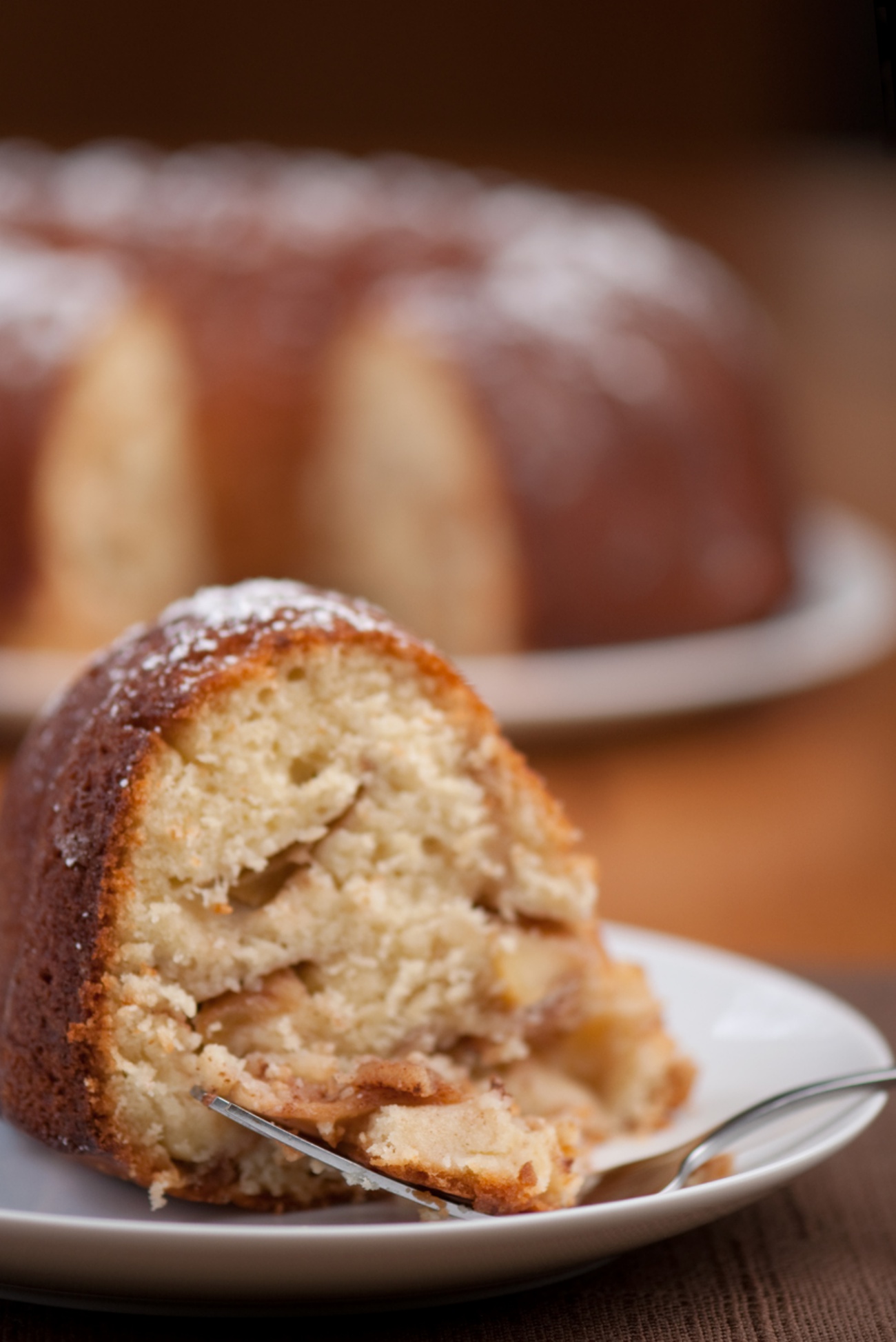 Slice of apple bundt cake with more dessert in background