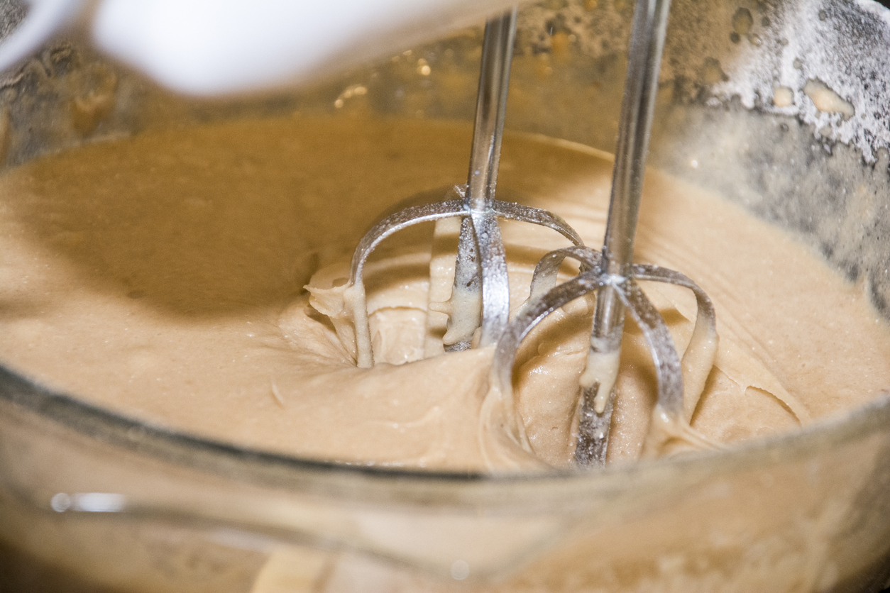 Electric mixer mixing cake mixture in a glass bowl