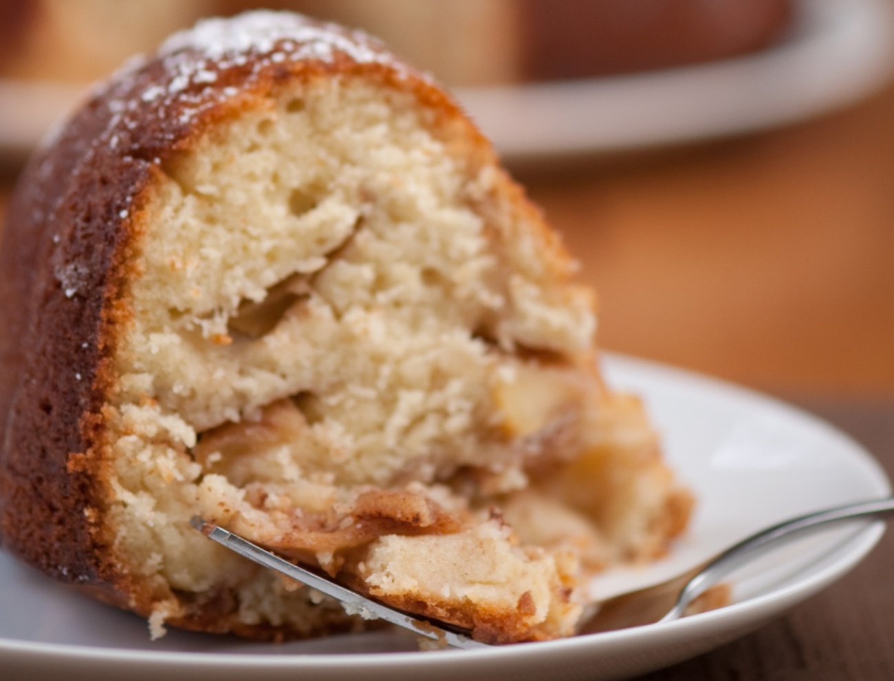 Slice of apple bundt cake with more dessert in background