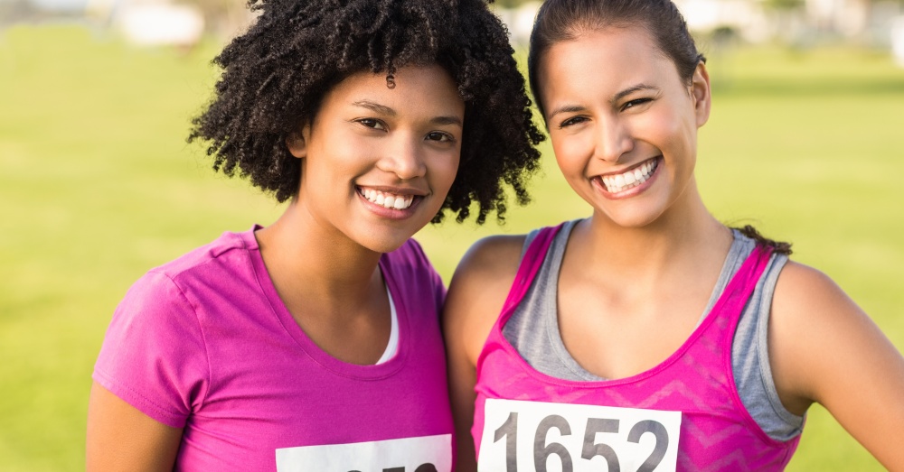 Two women athletes smiling and posing for the camera with their arms around each other