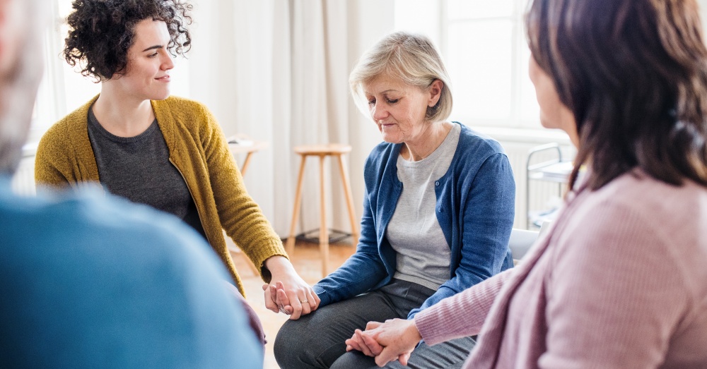 A group of women sitting in a circle holding hands