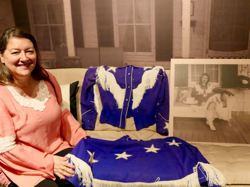 Patsy Cline's daughter, Julie Fudge, posing with her mother's cowgirl outfit