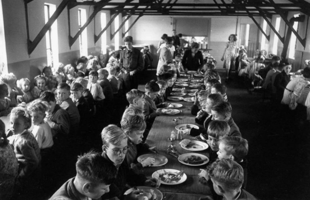 An overcrowded dining hall at Walsgrave Colliery School near Coventry, England filled with children of the post-war baby boom, 1952.