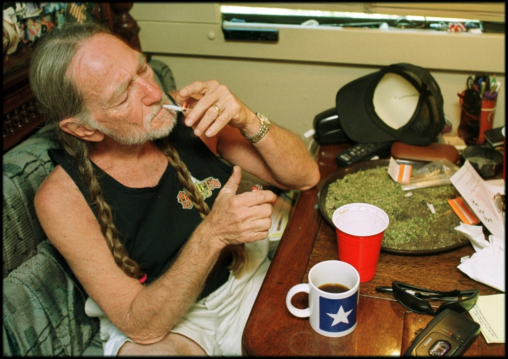 American country singer Willie Nelson takes a drag off a joint while relaxing at his home in Texas, 2000s.