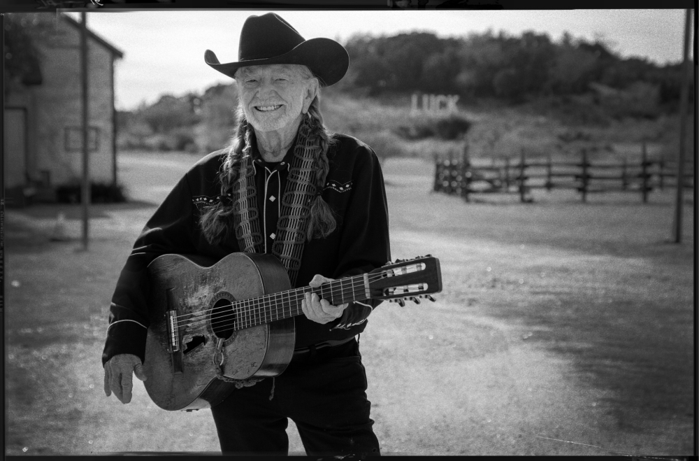 Willie Nelson posing with his guitar