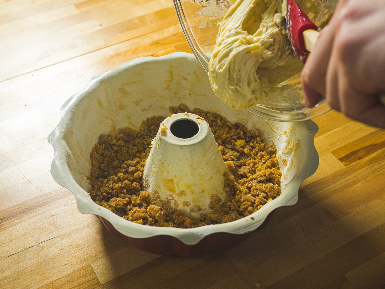 adding topping and batter to bundt pan for sour cream coffee cake