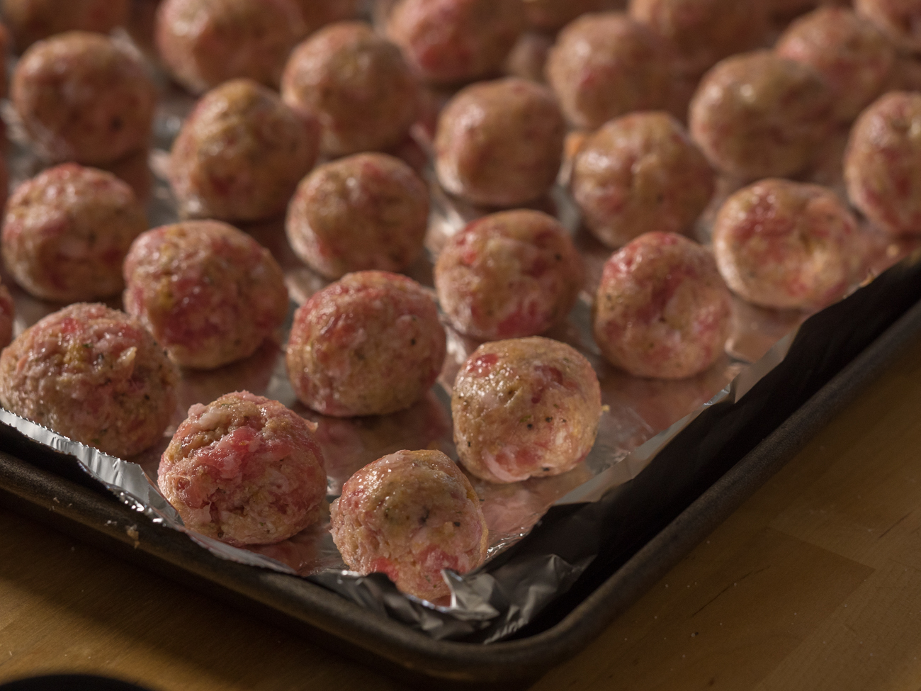 raw meatballs on a foil-lined baking sheet