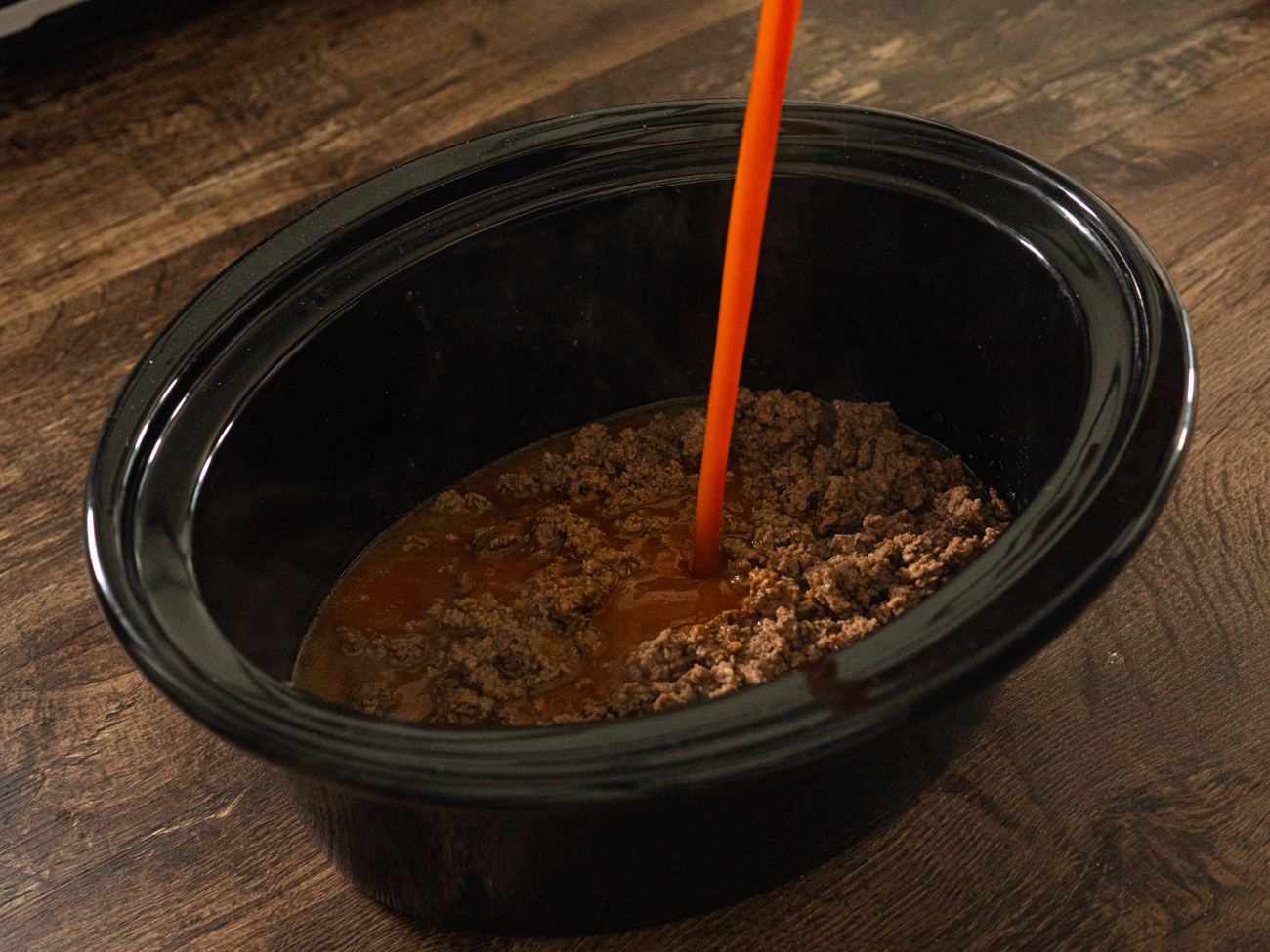V8 being poured into a slow cooker pot