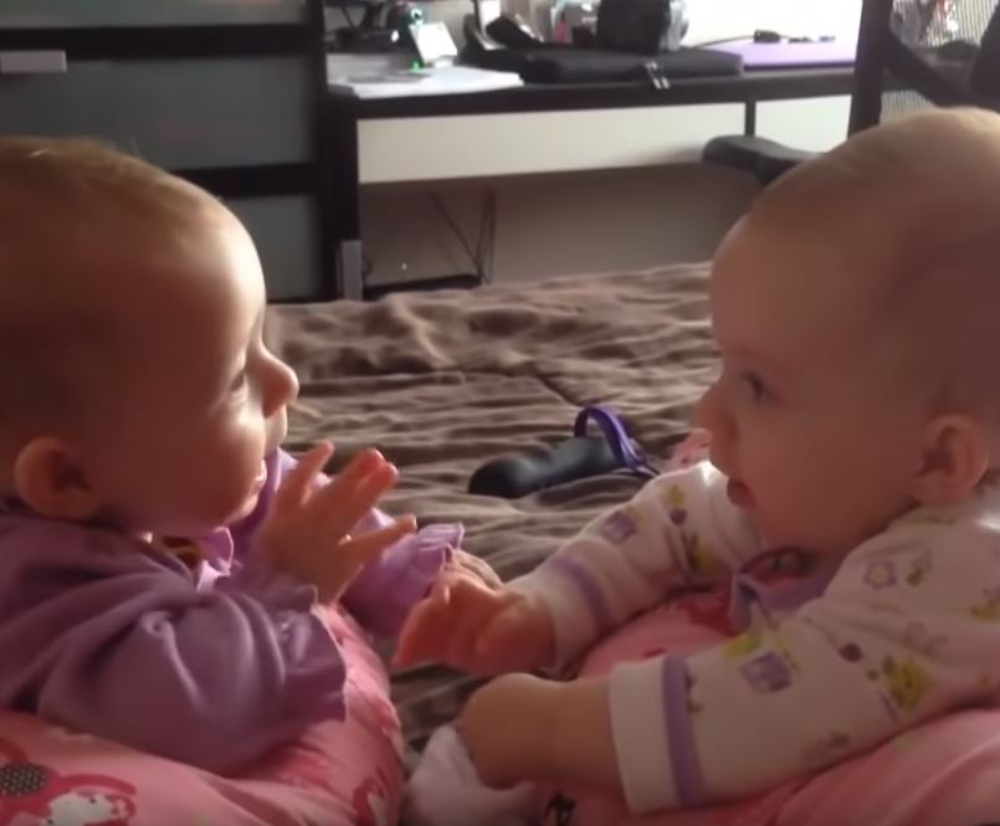 twin babies talking and holding hands