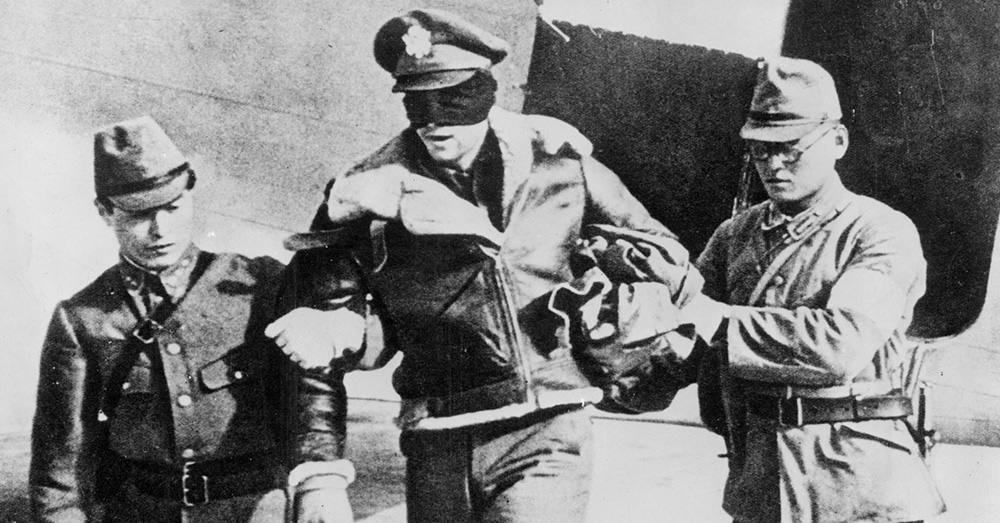 U.S. Army Air Force Lt. Robert L. Hite, blindfolded by his captors, is led from a Japanese transport plane after he and the other seven flyers were flown from Shanghai to Tokyo.