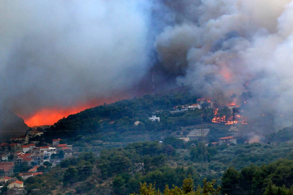 Aerial view of wildfire spreading through forest and buildings