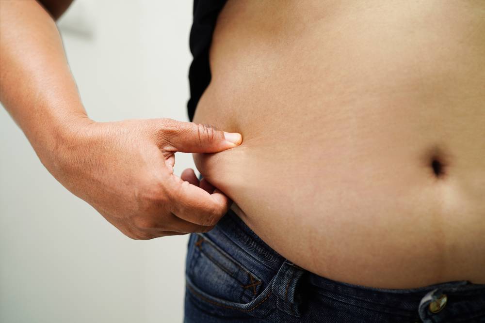 Man pinches the fat around his stomach